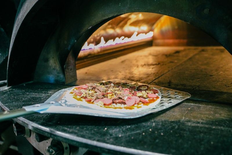 Pizza factory open kitchen with wood fire oven and bar seating